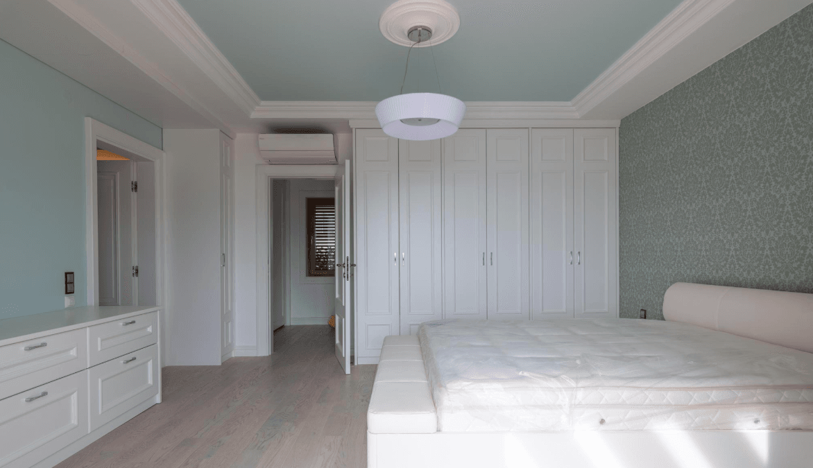 Bright bedroom with white furniture, built-in wardrobe, and bed in a villa in Bijela, Montenegro. Modern interior.