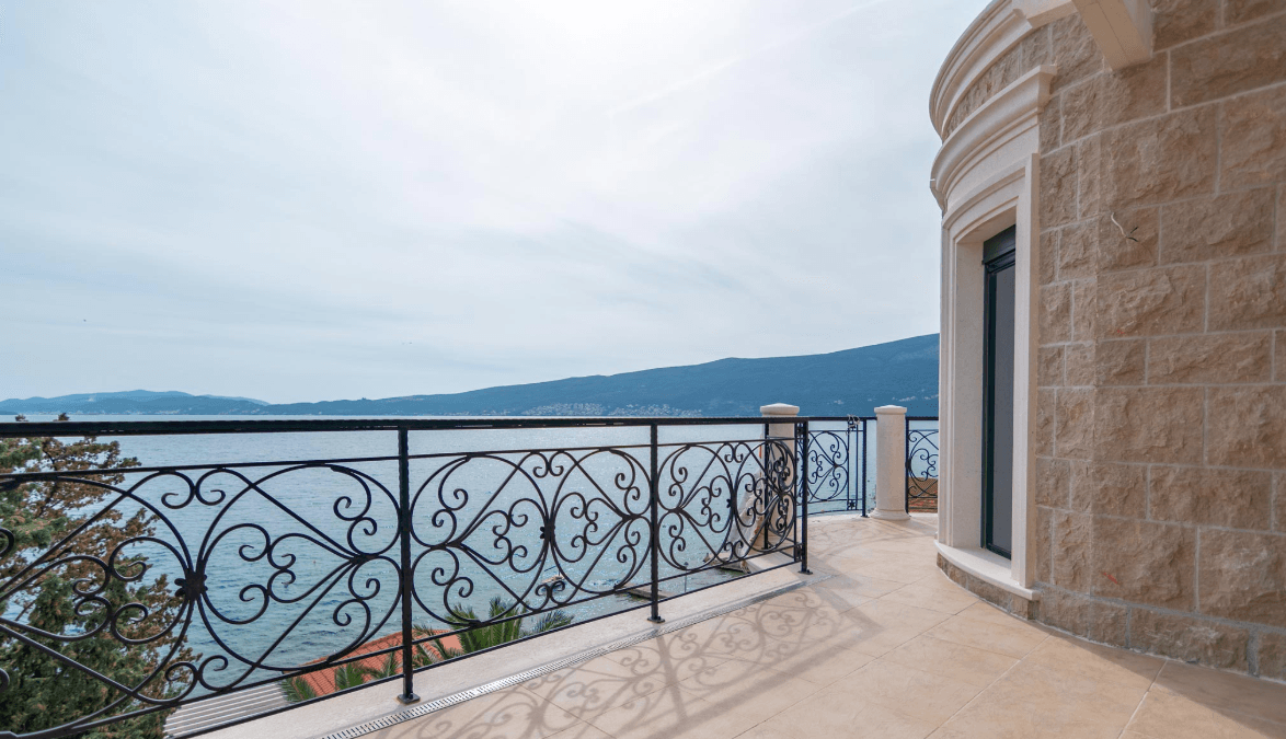 Spacious terrace of a villa in Bijela, Montenegro, with wrought-iron railing and panoramic views of the sea and mountains.