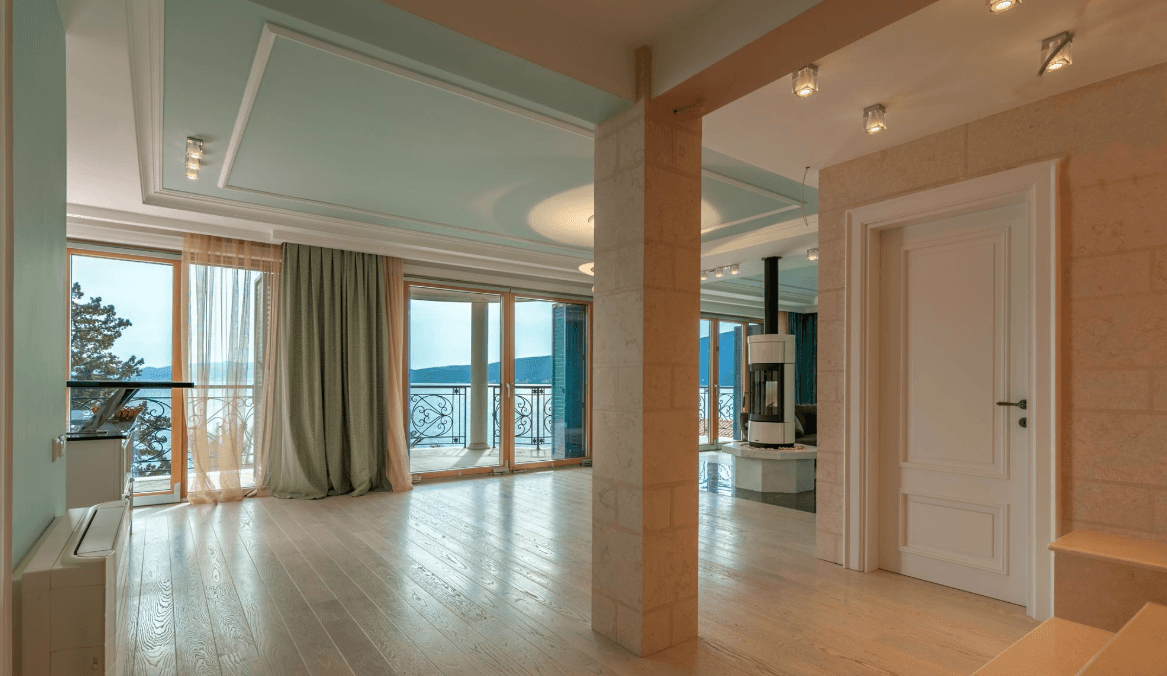 Living room with a fireplace and panoramic sea view in a villa, Bijela, Montenegro: bright interior, stone finishes.
