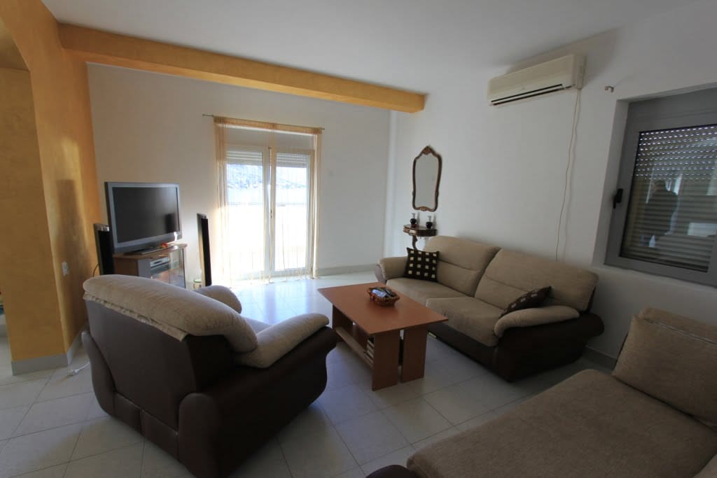 Living room in a mini-hotel in Orahovac, Montenegro: soft seating, coffee table, TV, and access to the terrace.