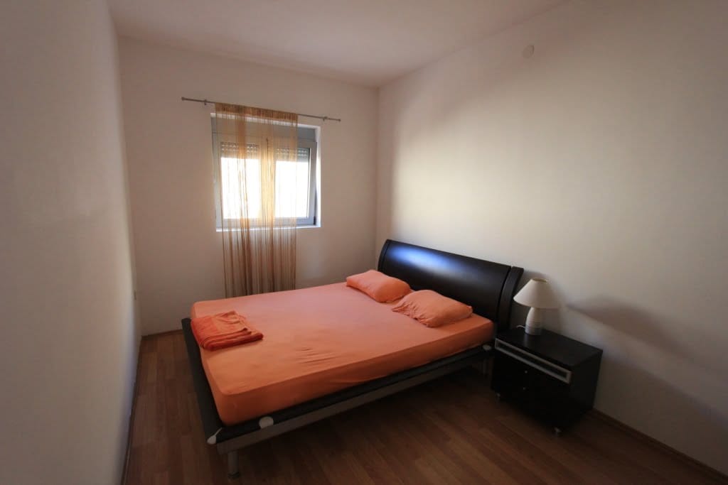 Bedroom with a double bed and bedside table in a mini-hotel, Orahovac, Montenegro. Light finishes, laminate flooring.