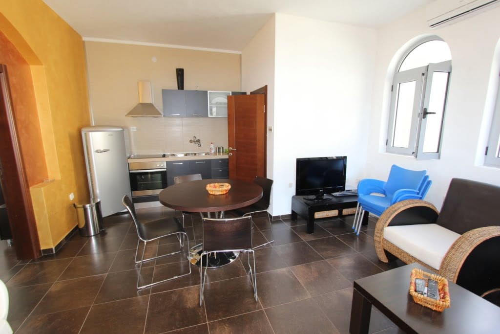 Living room with kitchen in a mini-hotel, Orahovac, Montenegro: dining area, modern furniture, and arched windows.