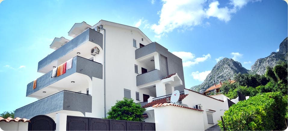 Modern mini-hotel in Orahovac, Montenegro: a three-story building with balconies against a backdrop of mountains and greenery.