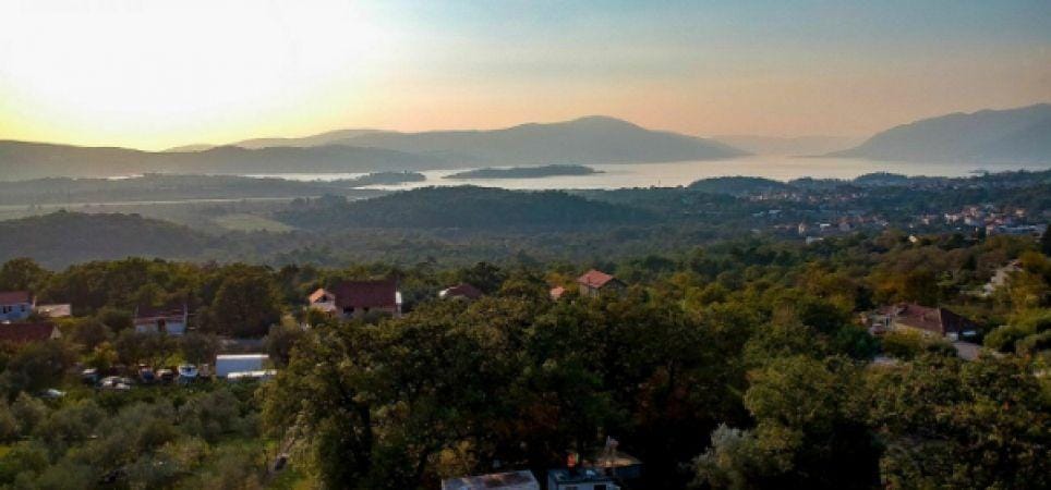 Panoramic view of the mountains and bay from a residential complex in Kavac, Montenegro: a picturesque landscape with greenery at sunset.