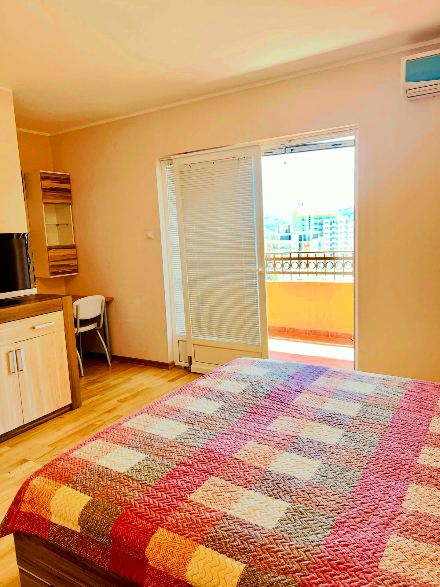 Bedroom in an apartment in Petrovac, Montenegro: double bed, light-colored furniture, access to a balcony with city views.