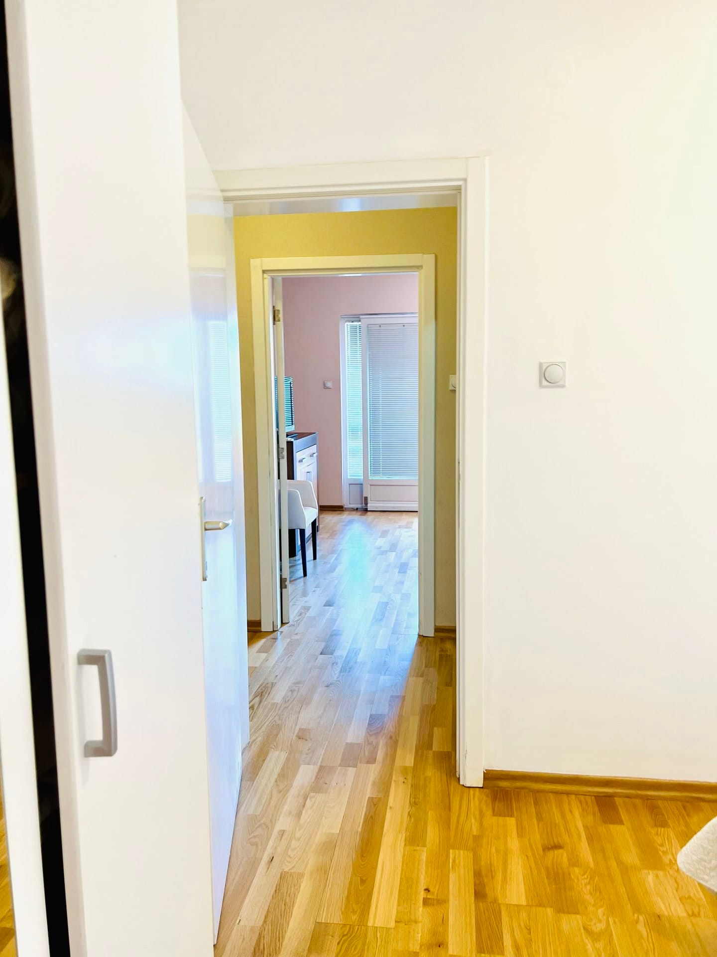 View from the room into a bright living room with parquet flooring and access to the balcony in an apartment, Petrovac, Montenegro.