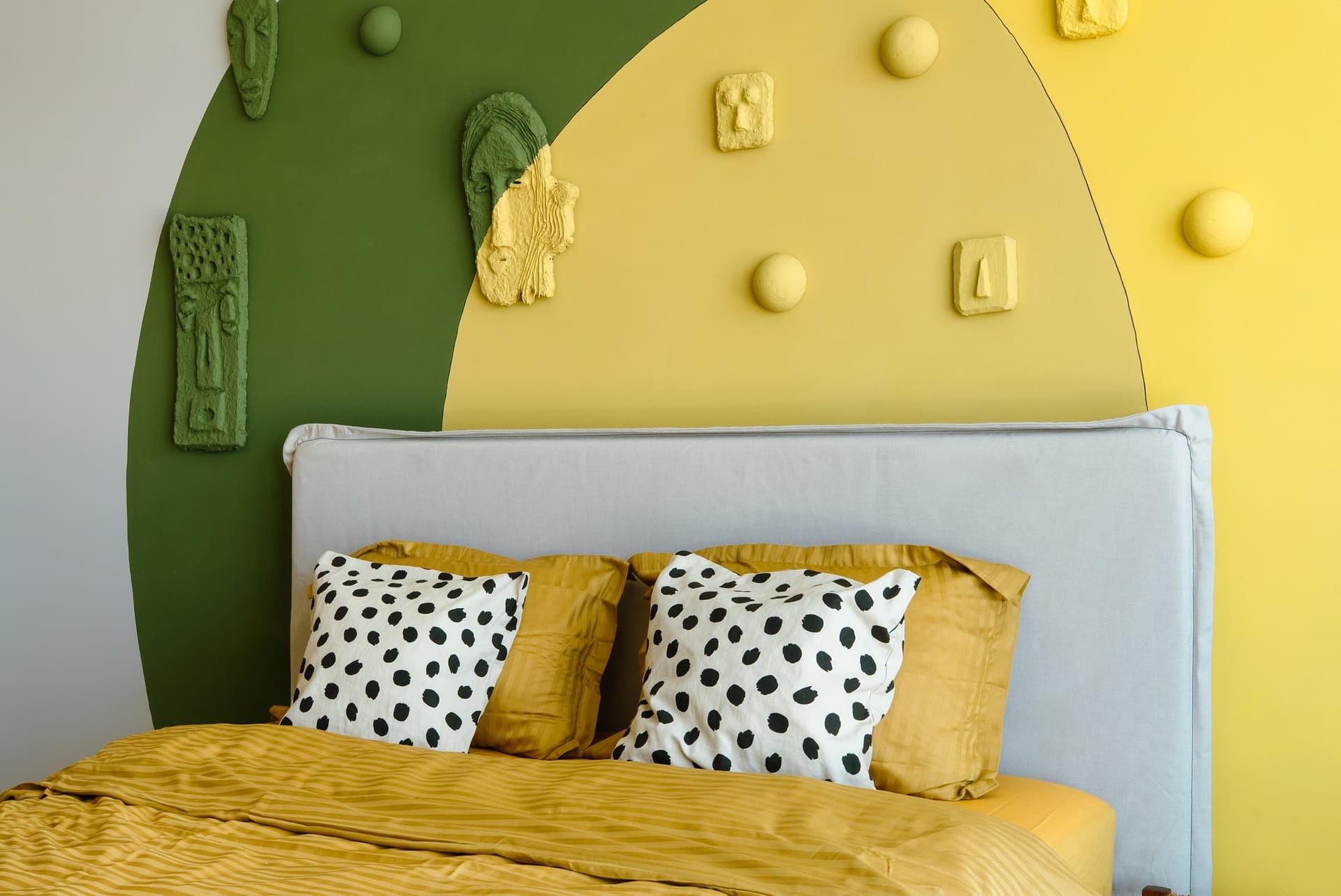 Designer bedroom with yellow-green wall decor in a villa in Krašići, Montenegro: a double bed with bright textiles.