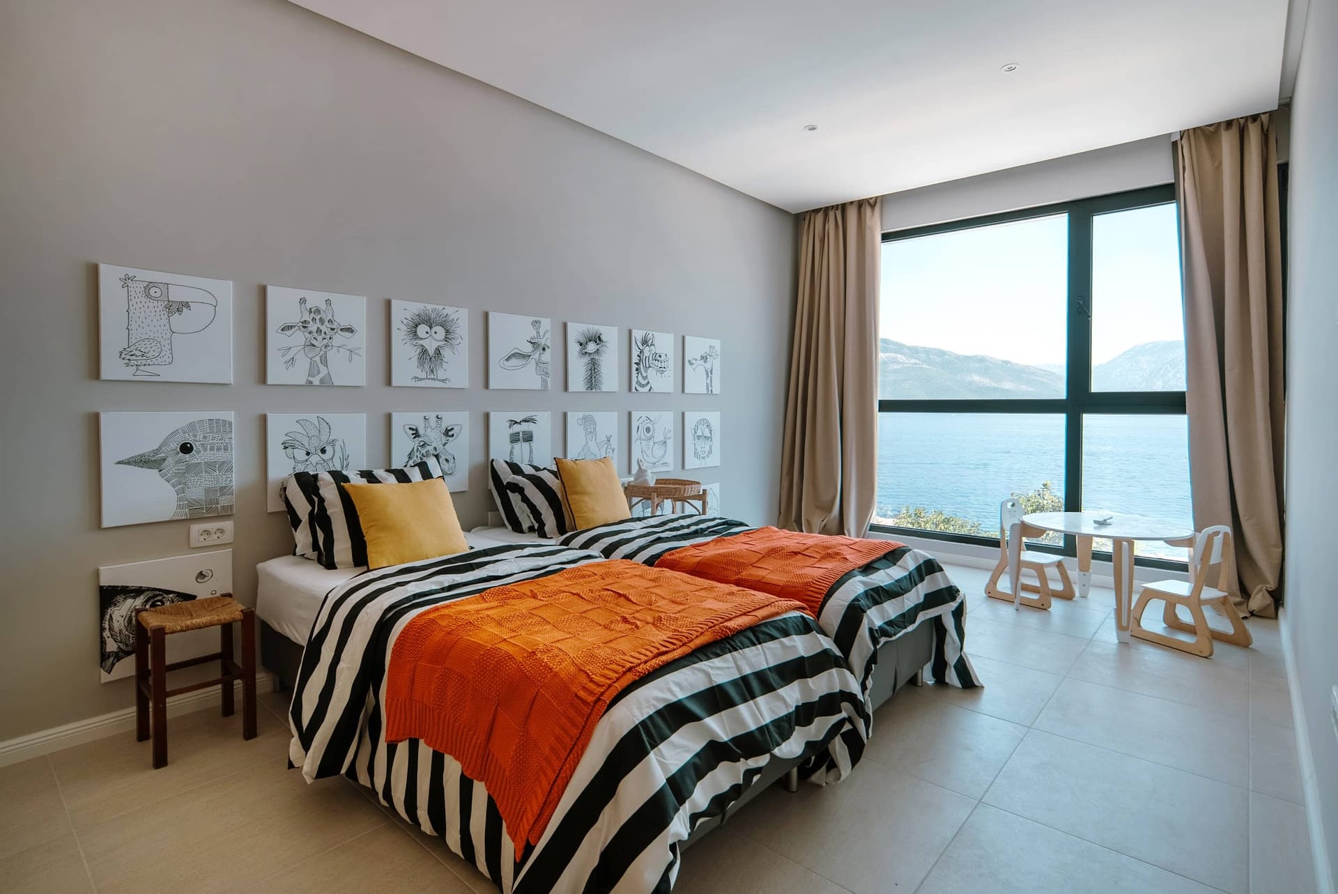 Children's bedroom with sea view in a villa in Krašići, Montenegro: two beds, animal-themed decor, and panoramic windows.