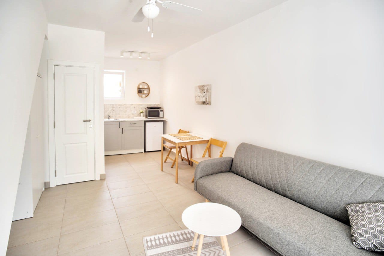 Living room with kitchen in a duplex, Baošići, Montenegro: gray sofa, dining table, and light interior finishes.