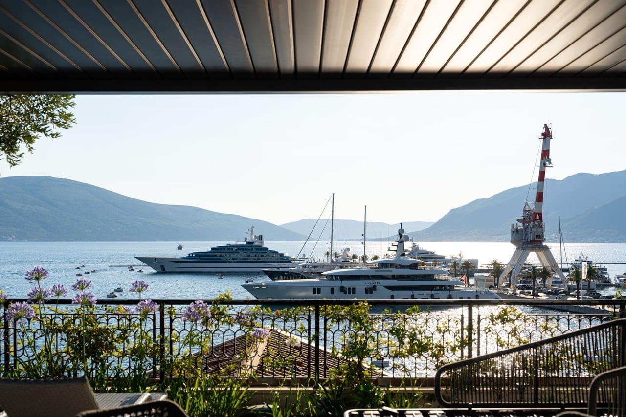 View from the apartment balcony in Porto Montenegro, Tivat, Montenegro: a panoramic view of the marina with yachts and mountains in the background.