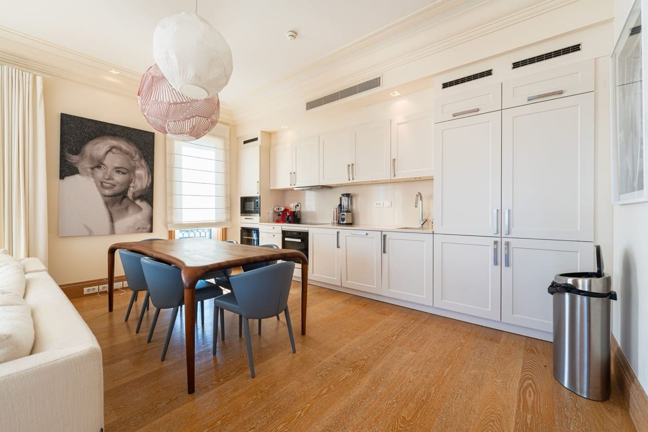 Modern kitchen-dining room in an apartment in Porto Montenegro, Tivat, Montenegro: light cabinetry, wooden table, and decor.