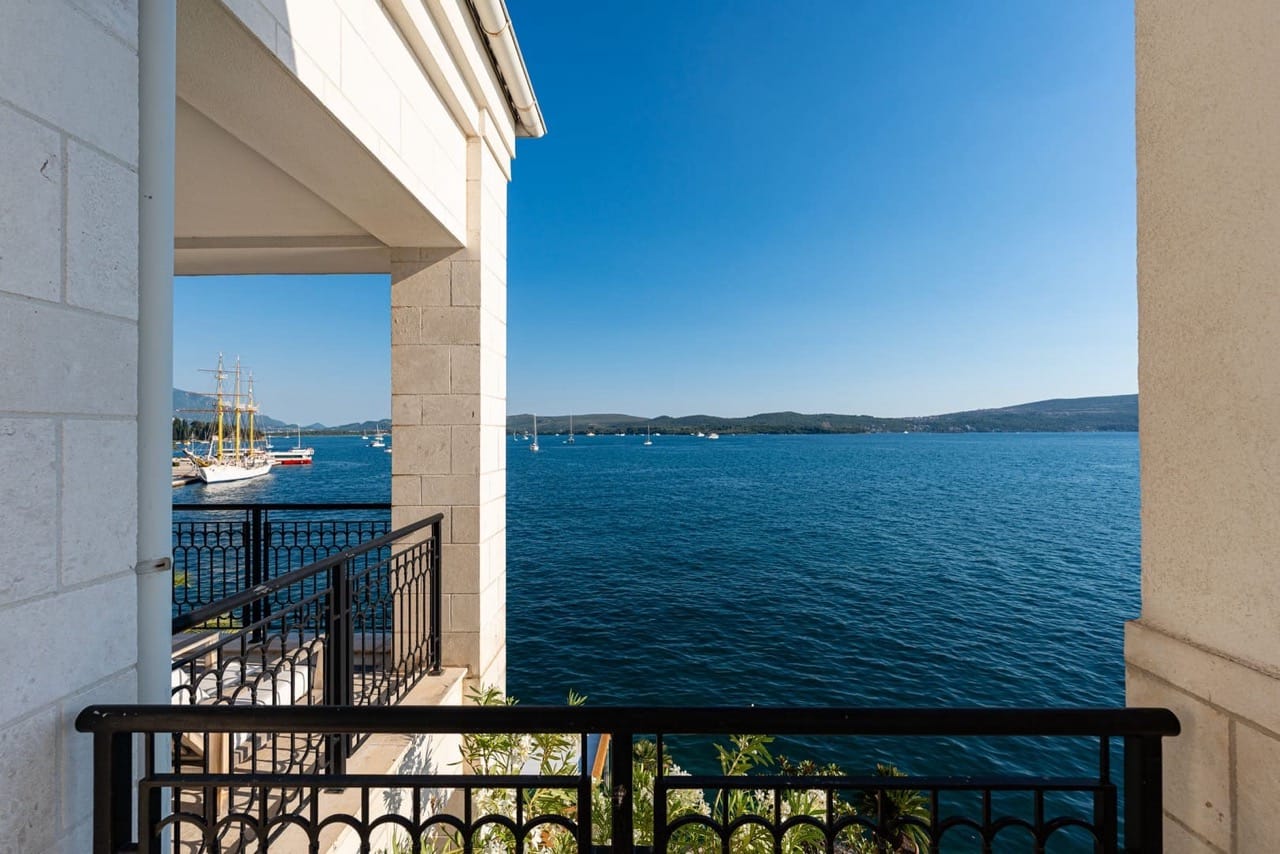 View from the balcony of the sea and yachts in Porto Montenegro, Tivat, Montenegro. Stone facade finish and wrought-iron railings.