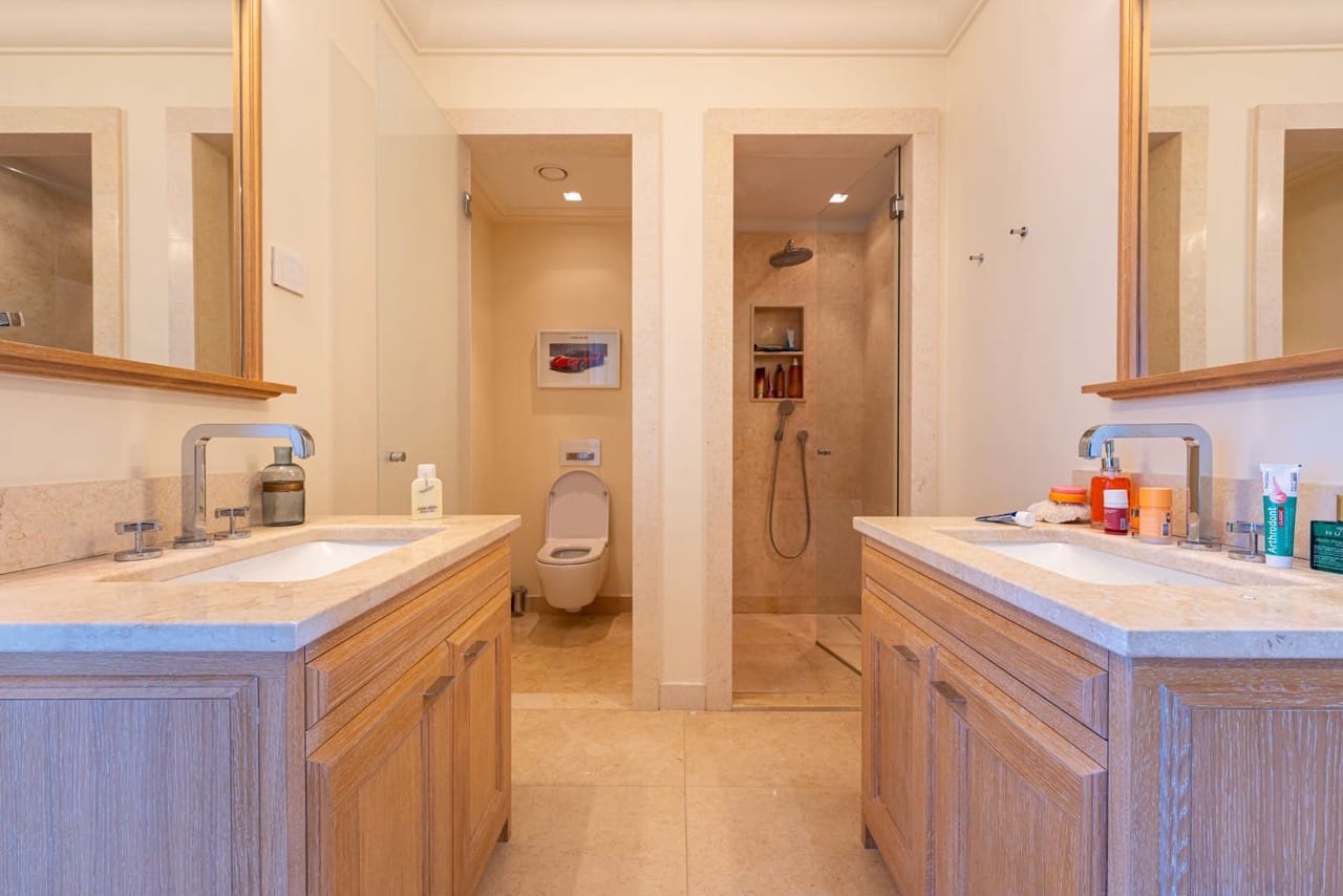 Bathroom with two sinks, a shower, and a toilet in an apartment in Porto Montenegro, Tivat, Montenegro.