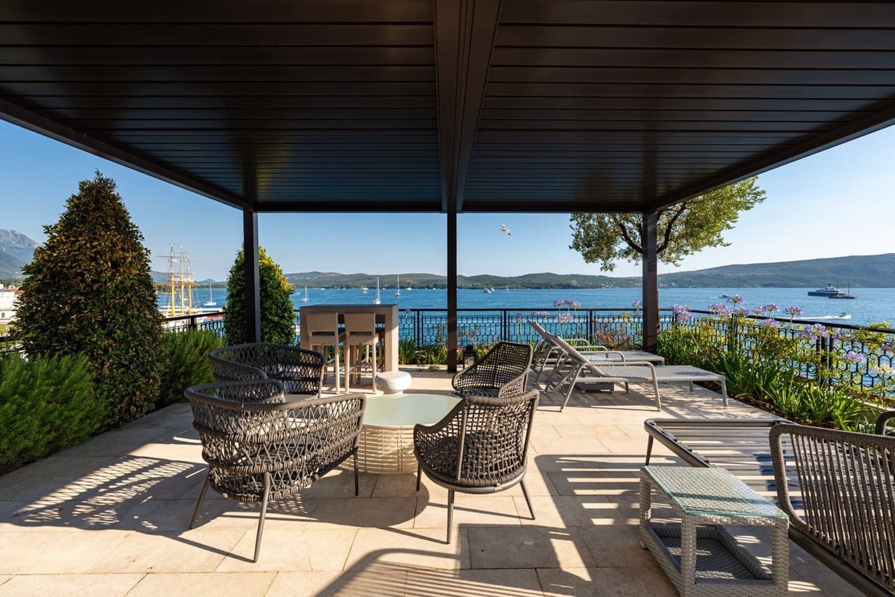 Terrace with wicker furniture and sea view in Porto Montenegro, Tivat, Montenegro. Open lounge area with a canopy.