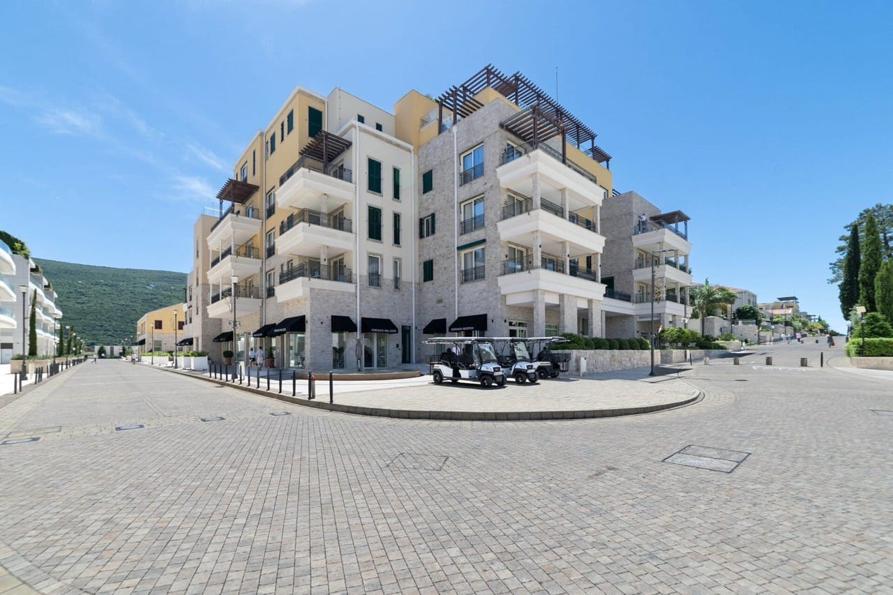 Modern Portonovi residential complex in Kumbor, Montenegro: building facade with terraces and golf carts in the parking lot.