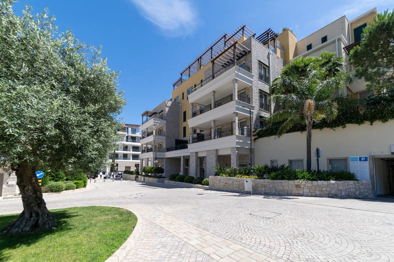 Modern residential complex in Portonovi, Kumbor, Montenegro: building facade with terraces, palm trees, and landscaped grounds