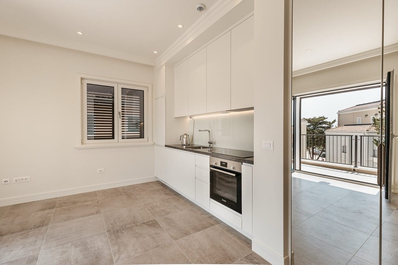 Modern kitchen with white cabinetry in an apartment at Lustica Bay, Radovici, Montenegro, with access to the terrace.