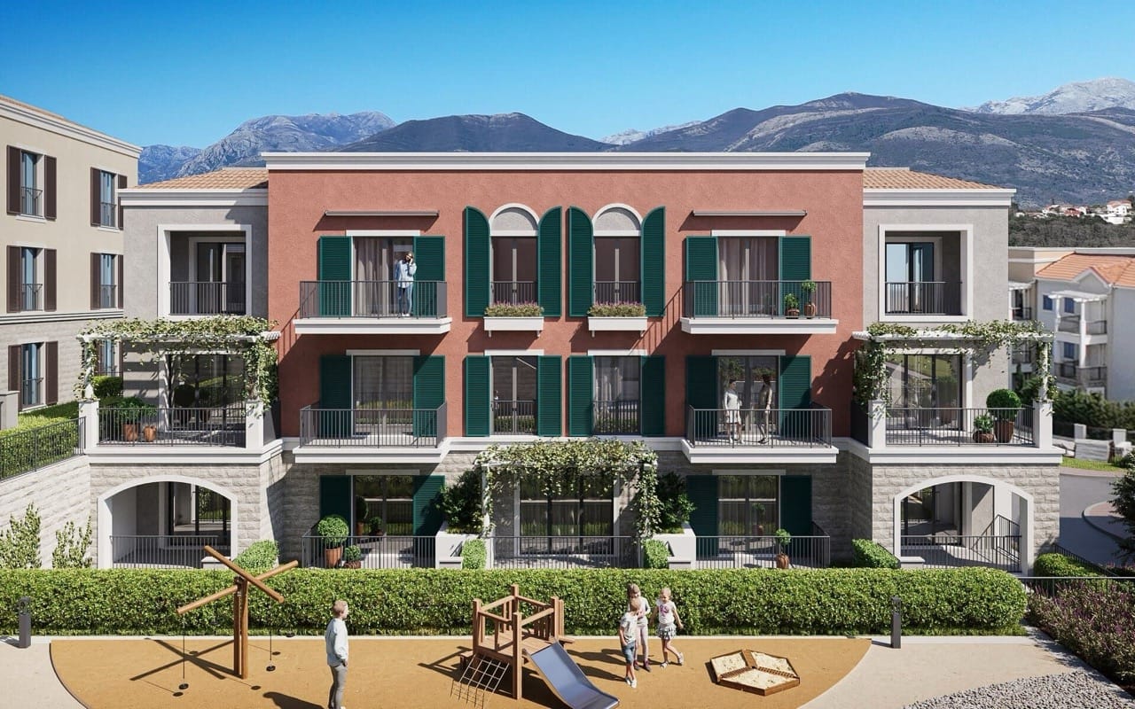 Facade of a residential complex in Luštica Bay, Radovići, Montenegro: terraces with green shutters and a playground by the building.