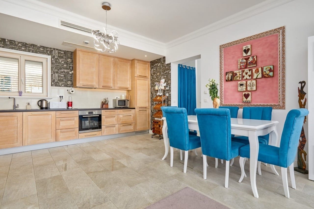 Kitchen-dining room with wooden cabinetry and blue chairs in an apartment in Luštica Bay, Radovići, Montenegro.
