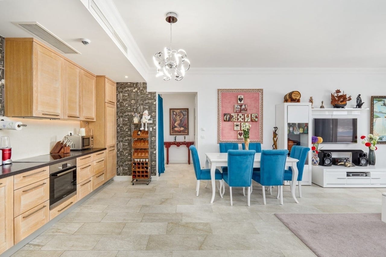 Living room with kitchen in an apartment in Luštica Bay, Radovići, Montenegro: light furniture, blue chairs, and a stylish interior.