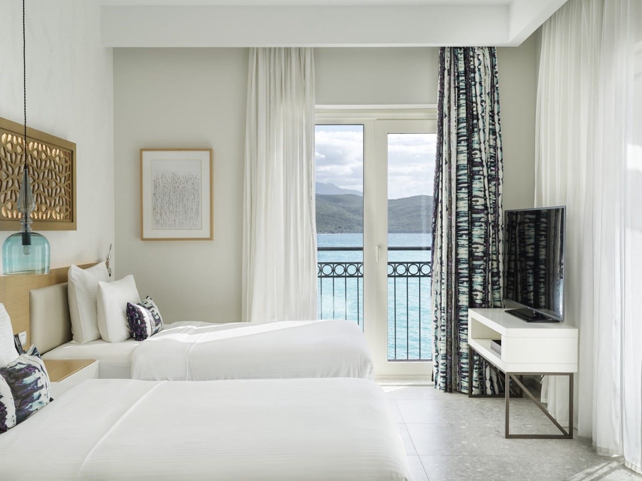Bedroom in Lustica Bay apartments, Radovici, Montenegro: two beds, modern furniture, and sea view from the balcony.