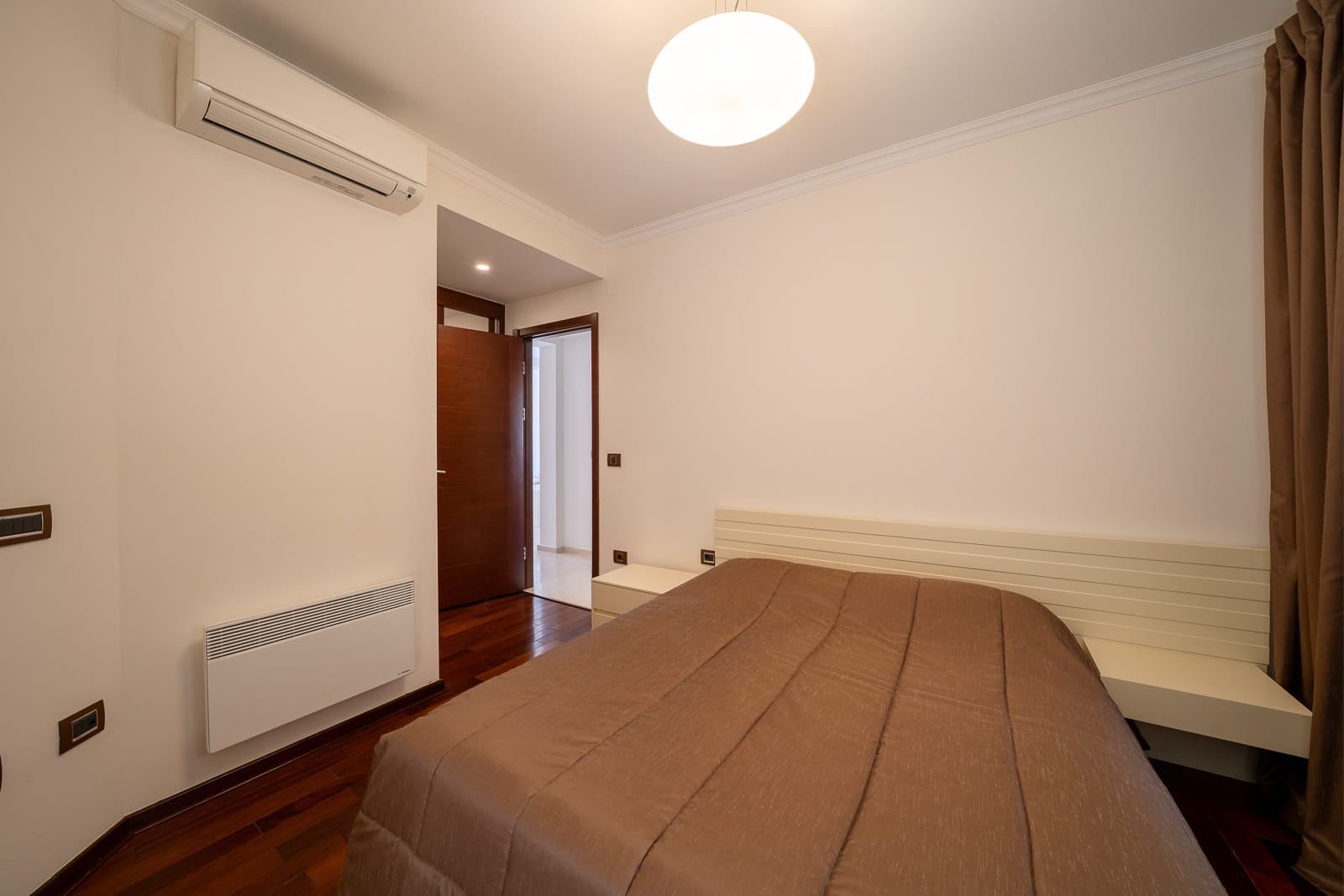 Bright bedroom with a double bed, air conditioning, and parquet flooring in an apartment for sale in Petrovac, Montenegro.