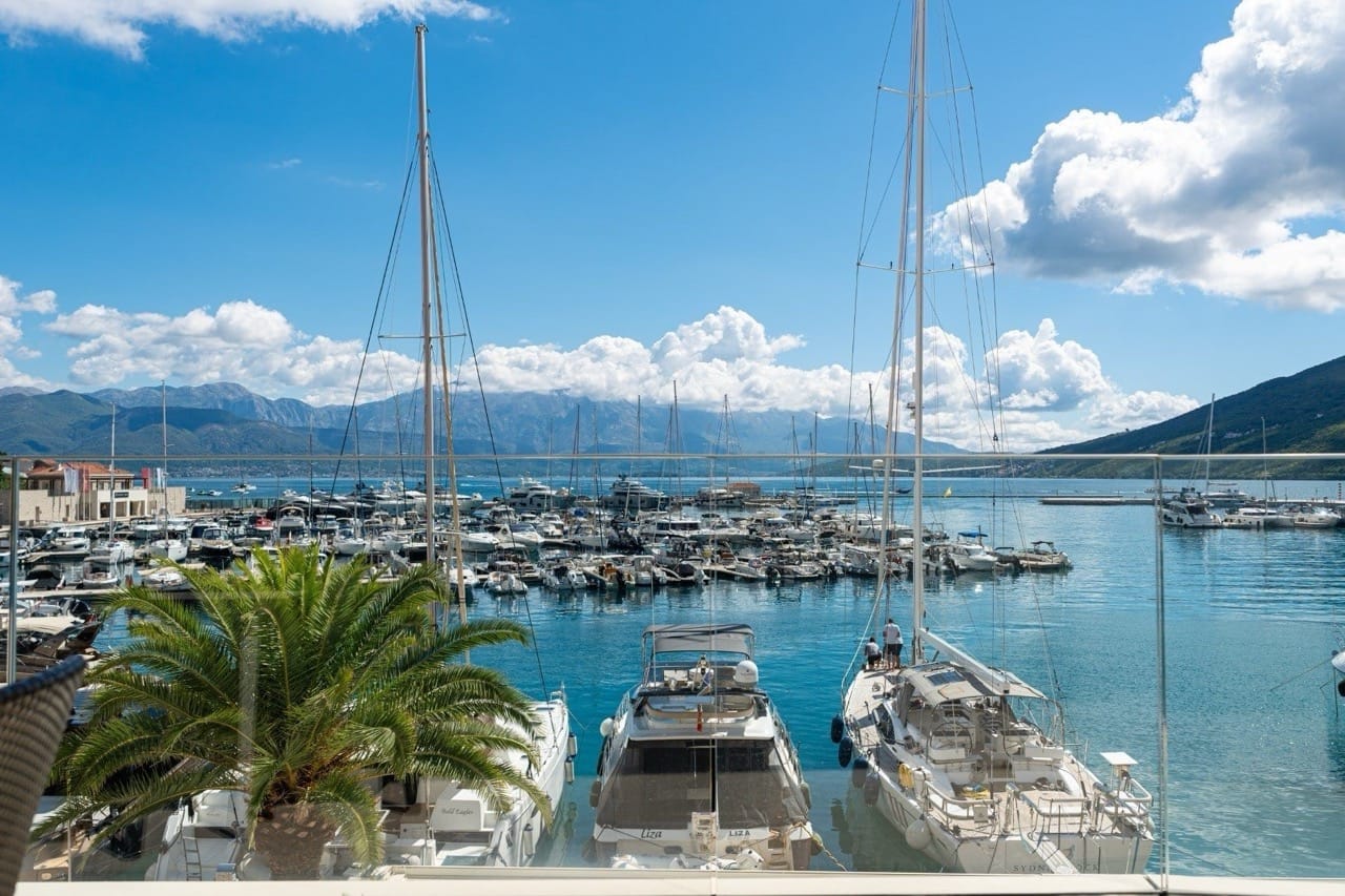 View from the apartment balcony in Portonovi, Kumbor, Montenegro: a panoramic yacht marina, moored yachts, and mountains.
