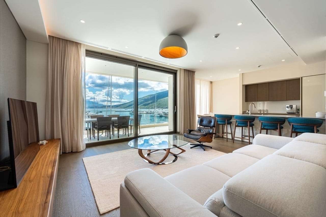 Living room with a view of the marina in Portonovi, Kumbor, Montenegro: modern furniture, panoramic windows, and an open-plan kitchen.