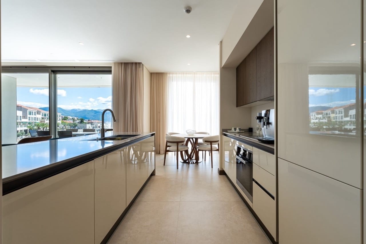 Modern kitchen in an apartment in Portonovi, Kumbor, Montenegro: glossy cabinets, dining area, and marina view.