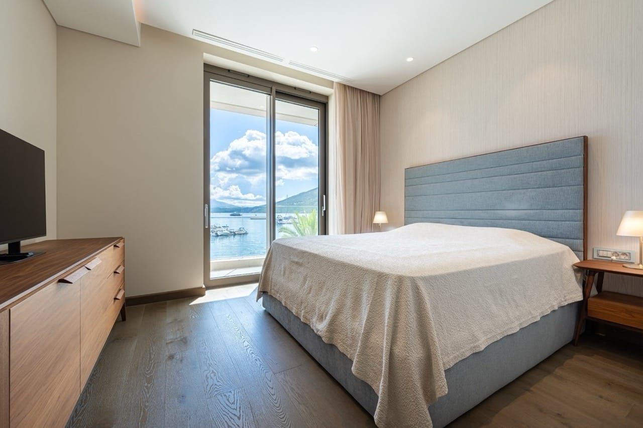 Modern bedroom in Portonovi, Kumbor, Montenegro with sea view, double bed, and wooden furniture.