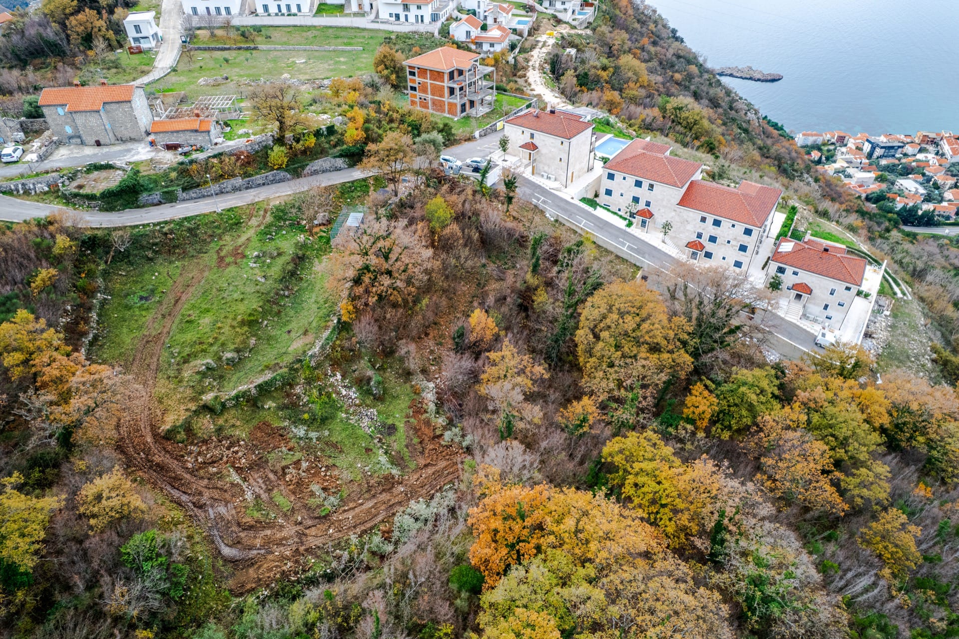 Aerial view of a residential complex in Blizikuće, Montenegro: modern houses with tiled roofs and a sea view.