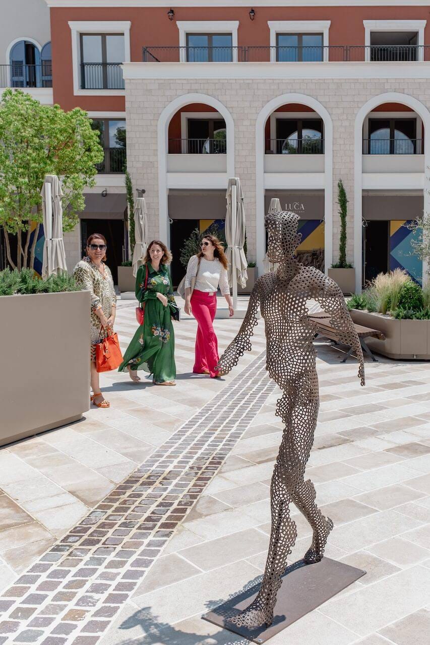 A modern square with an art installation and a promenade area of the luxury Lustica Bay residential complex in Montenegro.