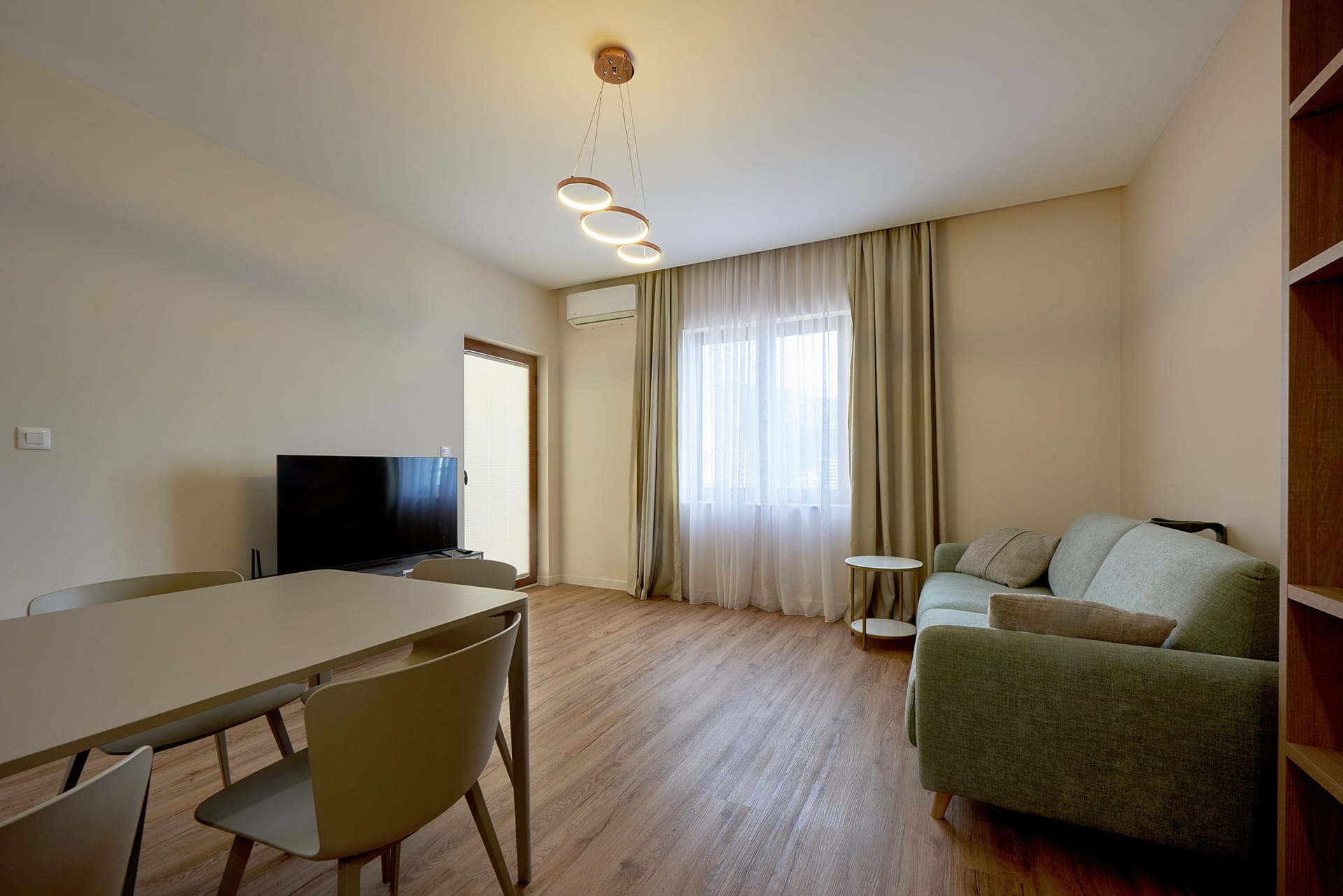Modern living room with a dining area and sofa in an apartment in Bečići, Montenegro. Bright interior with a TV zone.