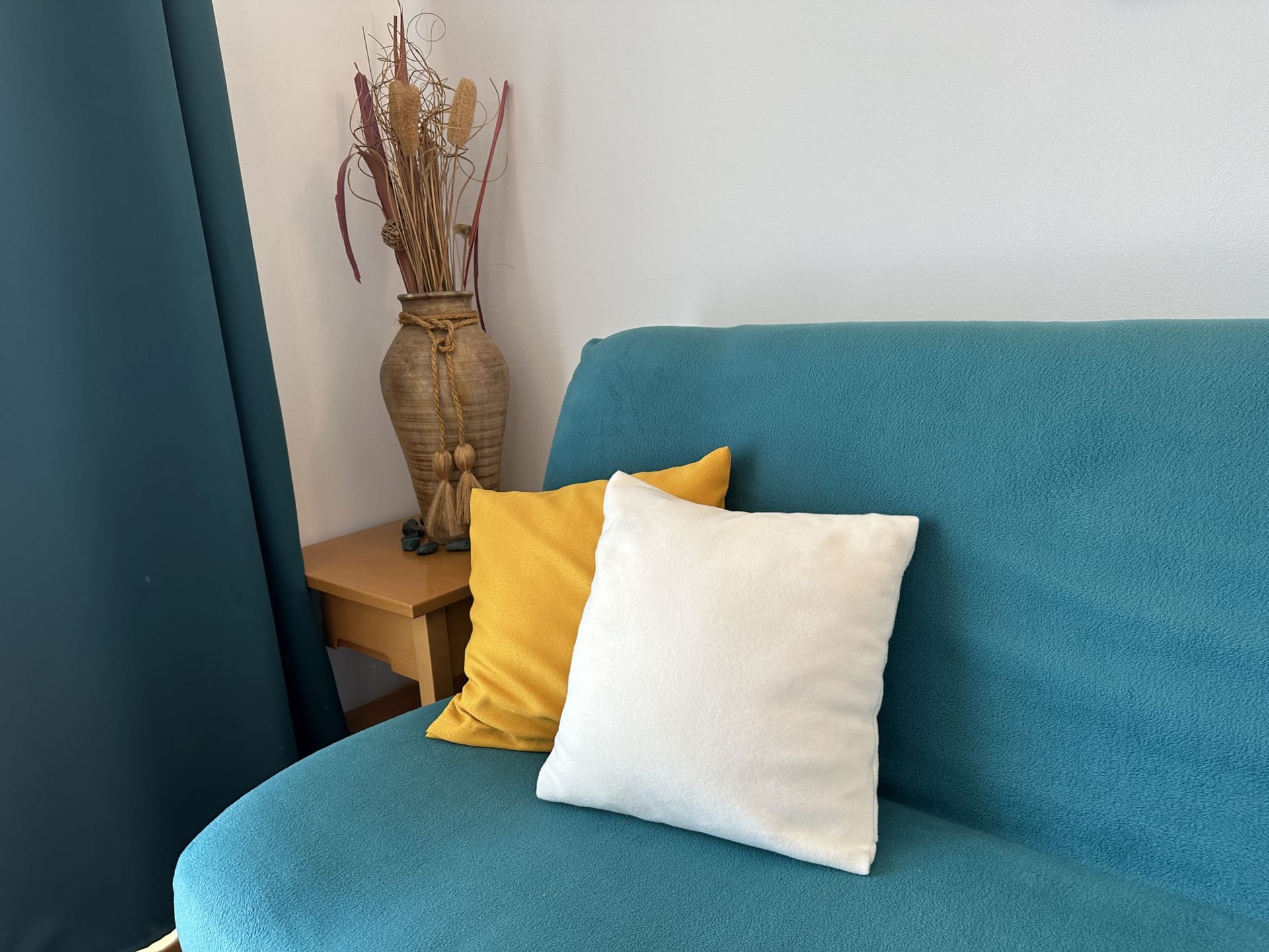 Turquoise sofa with decorative pillows in the interior of an apartment in Bečići, Montenegro. Cozy living room with decor.