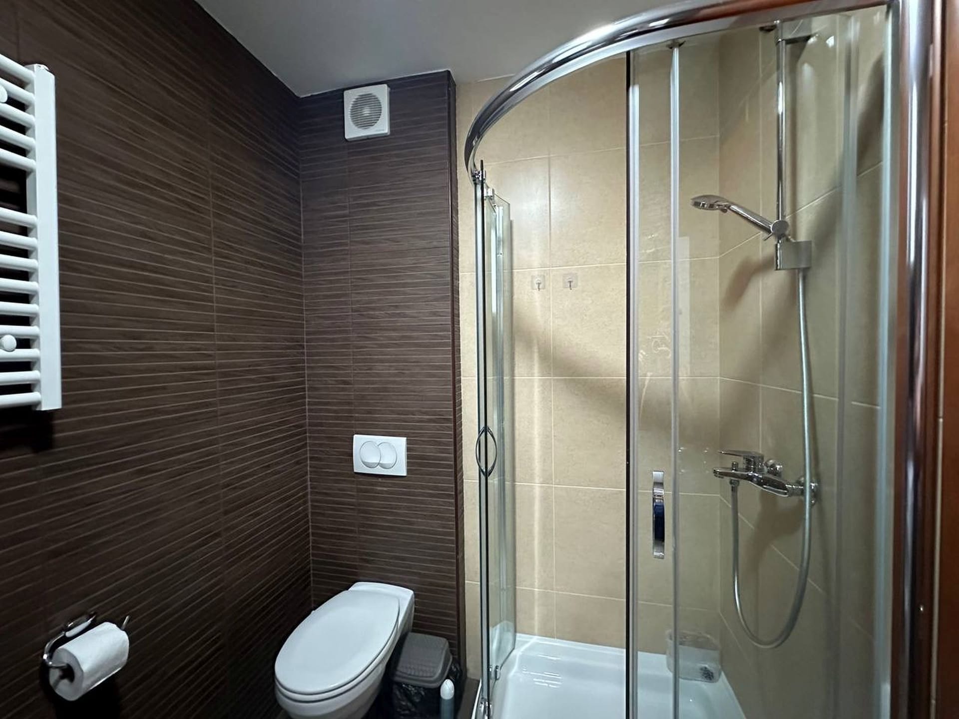 Modern bathroom in an apartment in Becici, Montenegro: walk-in shower, brown tiles, and sanitary ware.