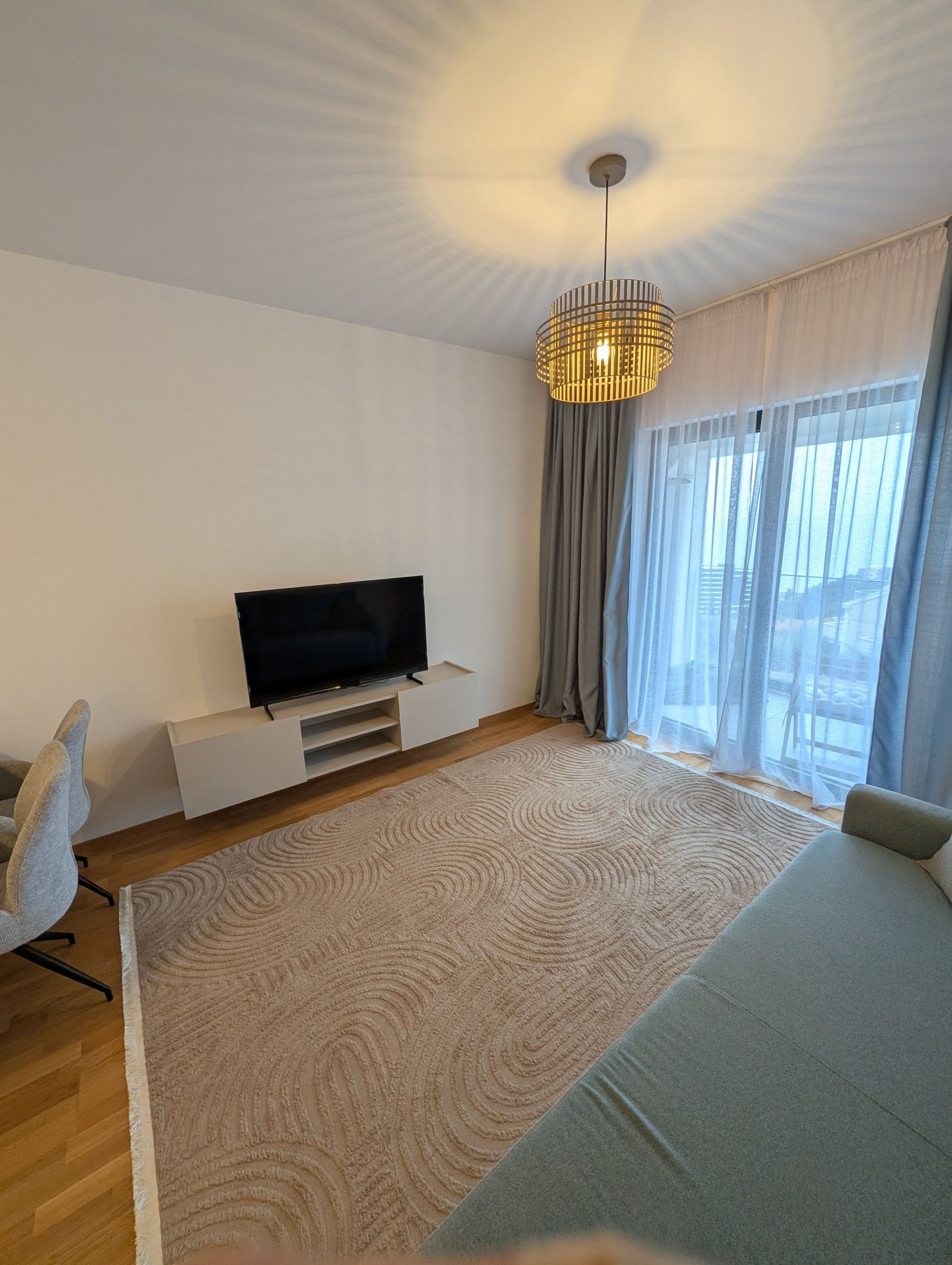 Modern living room in Bečići apartments, Montenegro: light furniture, TV area, panoramic window, and stylish decor.