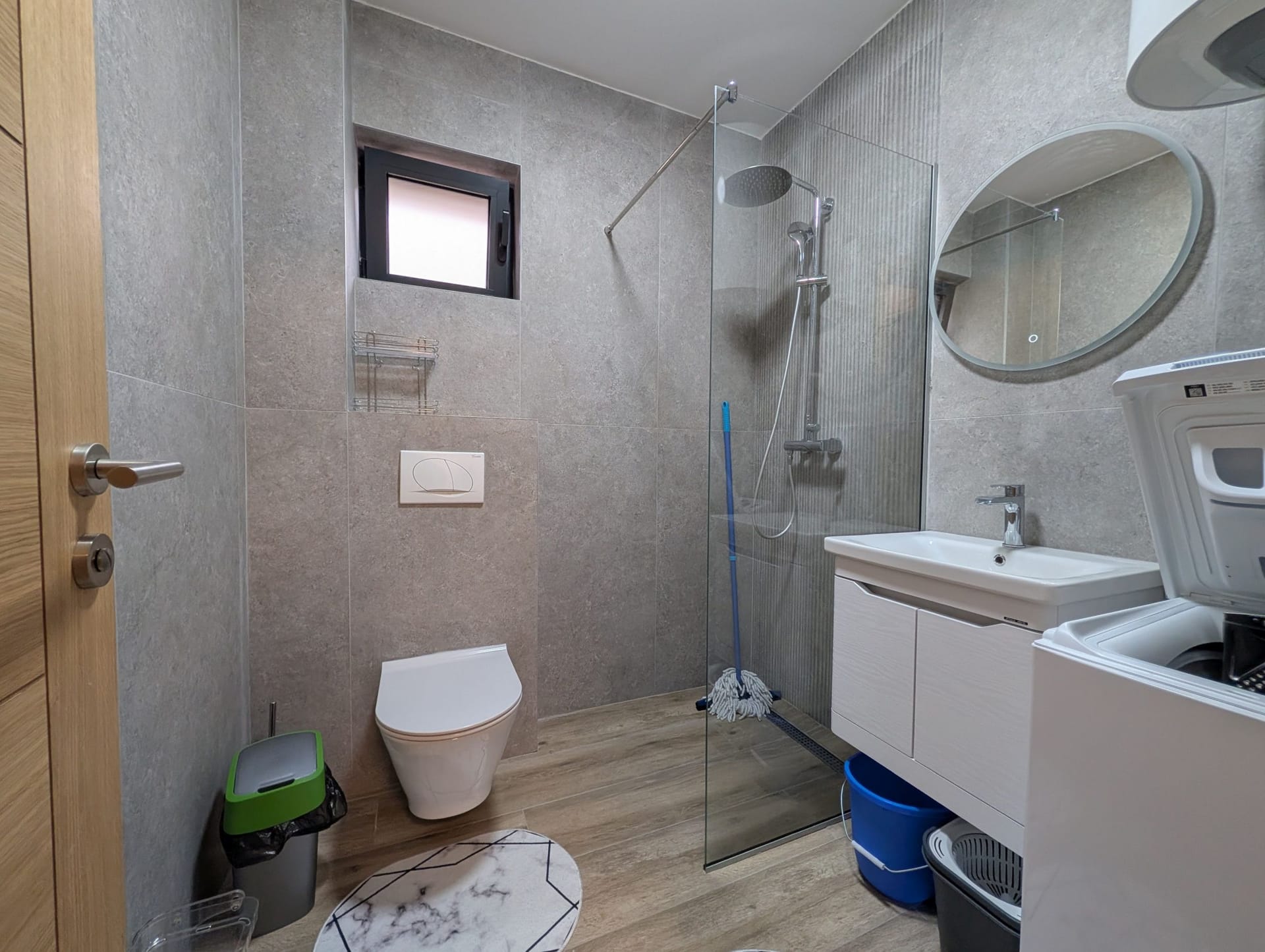 Modern bathroom in an apartment in Bečići, Montenegro: shower cabin, wall-hung toilet, and washing machine.