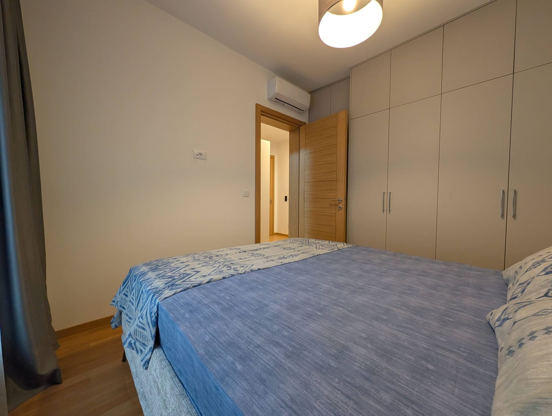 Modern bedroom in an apartment in Bečići, Montenegro: double bed, built-in wardrobe, and air conditioner.