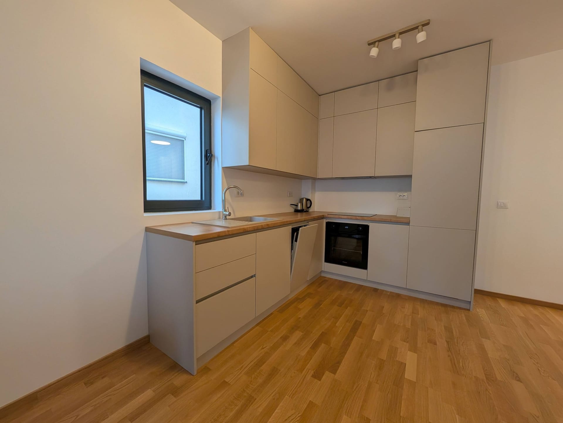 Modern bright kitchen with a wooden countertop in an apartment in Bečići, Montenegro. Built-in appliances and parquet flooring.