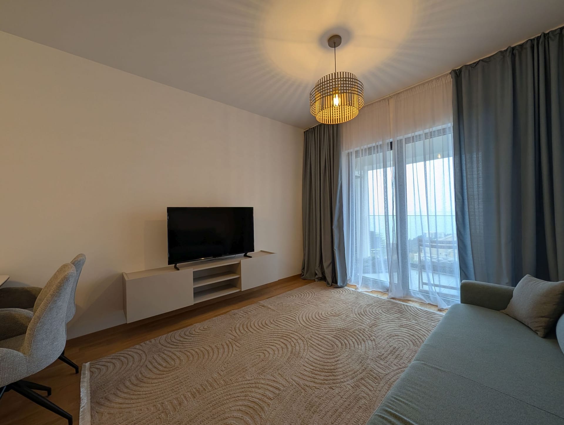 Modern living room in Bečići apartments, Montenegro: sofa, TV area, carpet, and access to a terrace with a sea view.