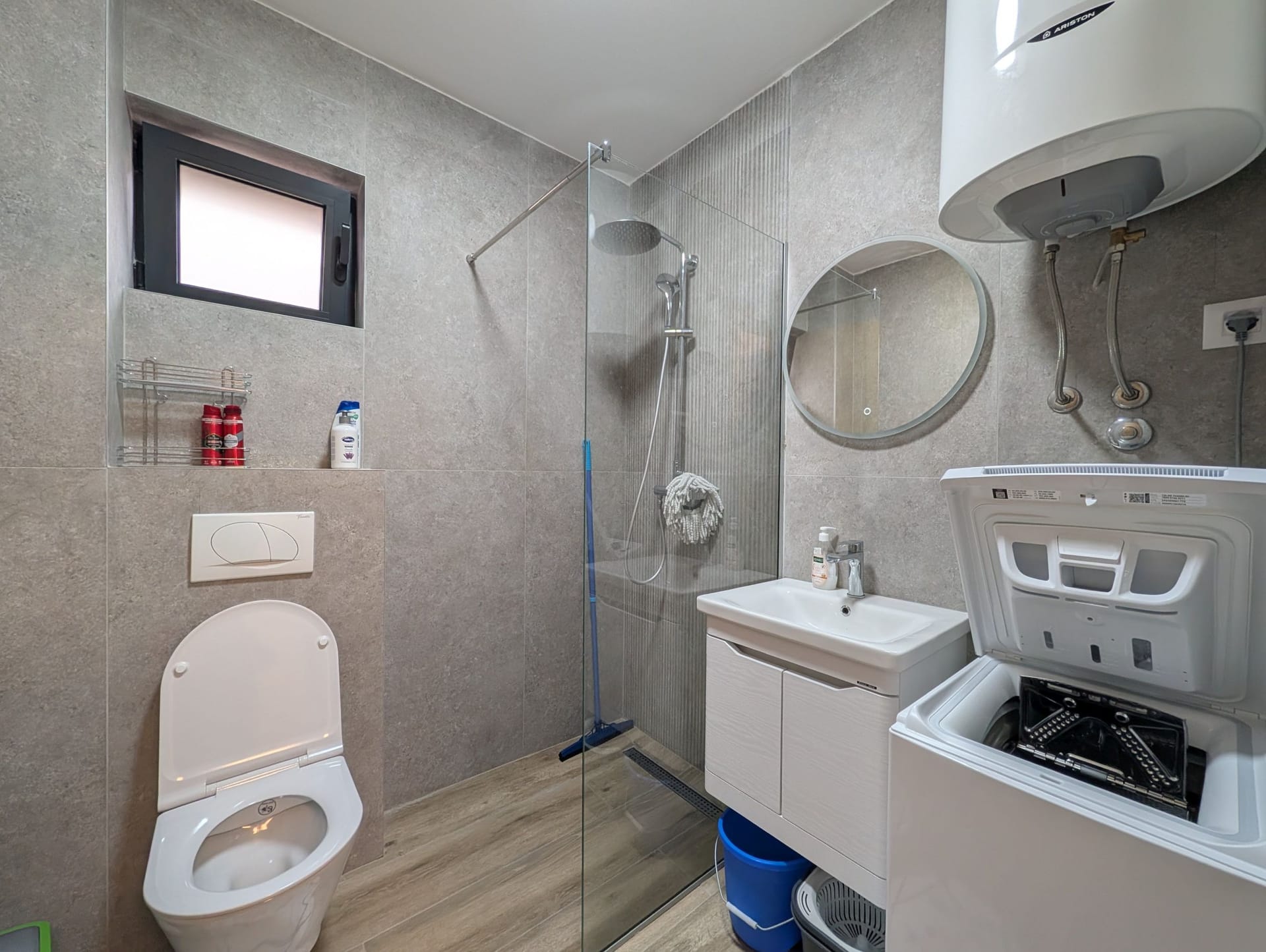 Modern bathroom in an apartment in Bečići, Montenegro: shower cabin, vanity unit with sink, and washing machine.