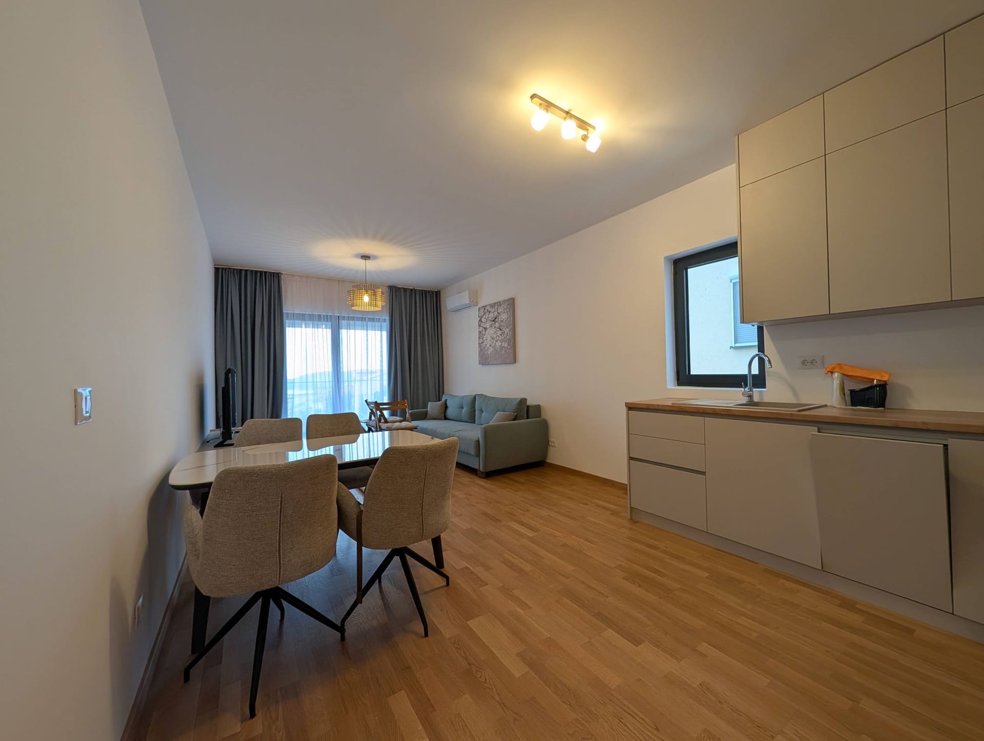 Modern living room with kitchen in an apartment in Bečići, Montenegro: dining area, sofa, and stylish interior finishes.