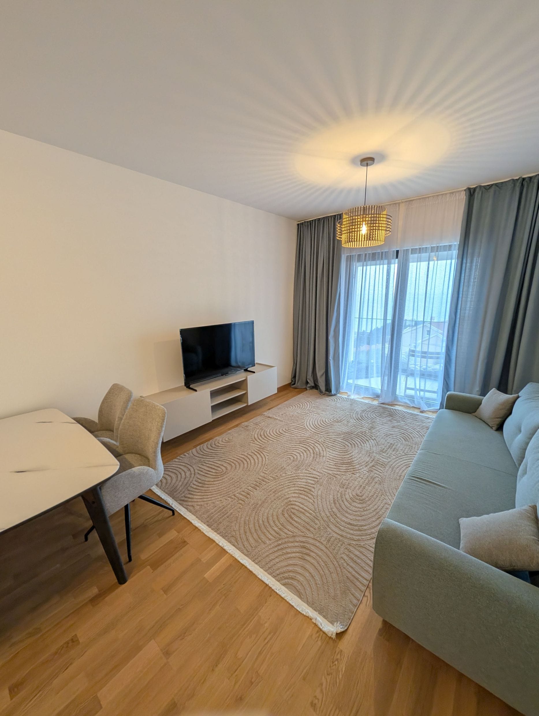 Modern living room in an apartment, Bečići, Montenegro: sofa, dining area, TV, and panoramic window with a view.
