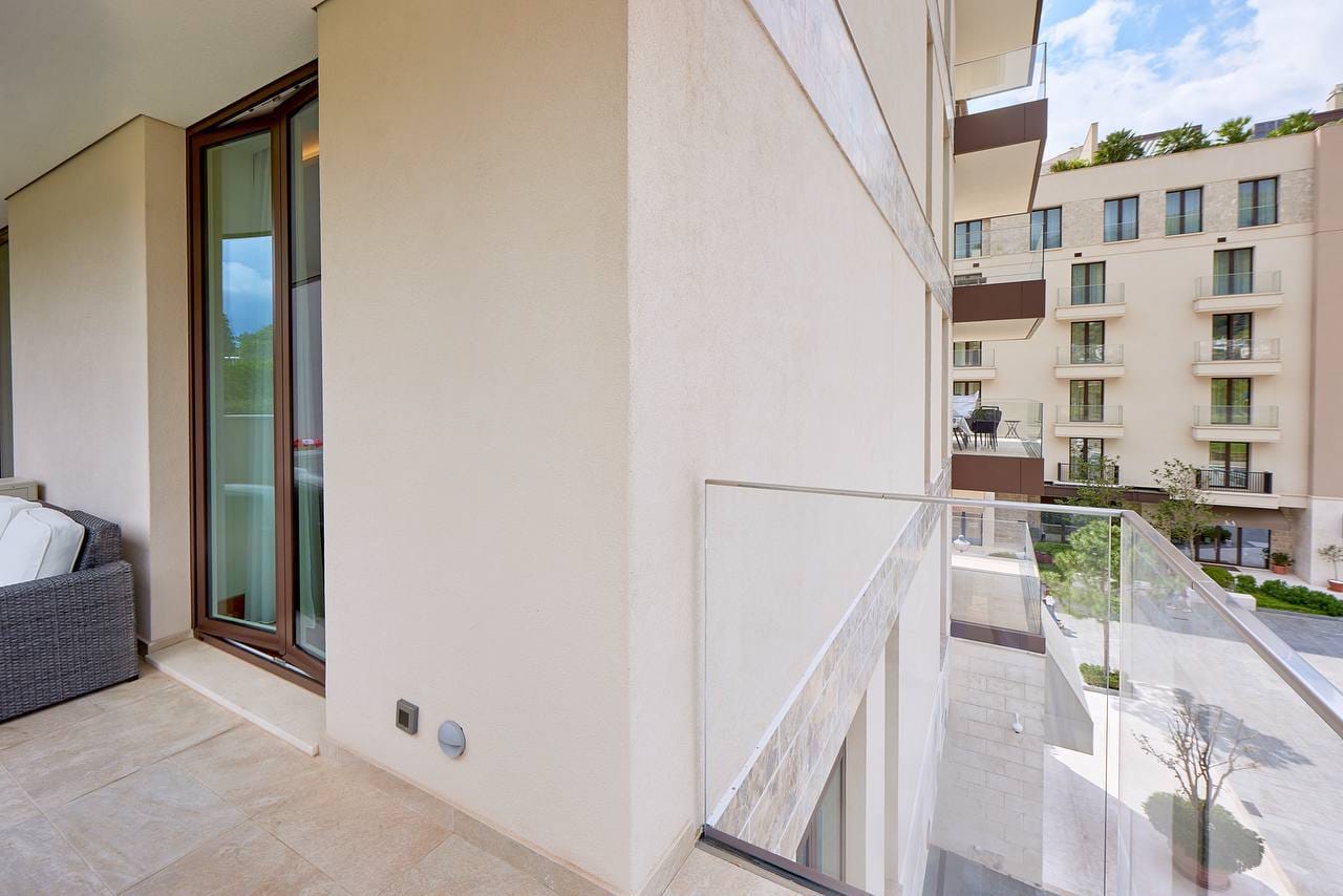 Balcony of a modern apartment in Porto Montenegro, Tivat, Montenegro, with panoramic glazing and a view of the complex.