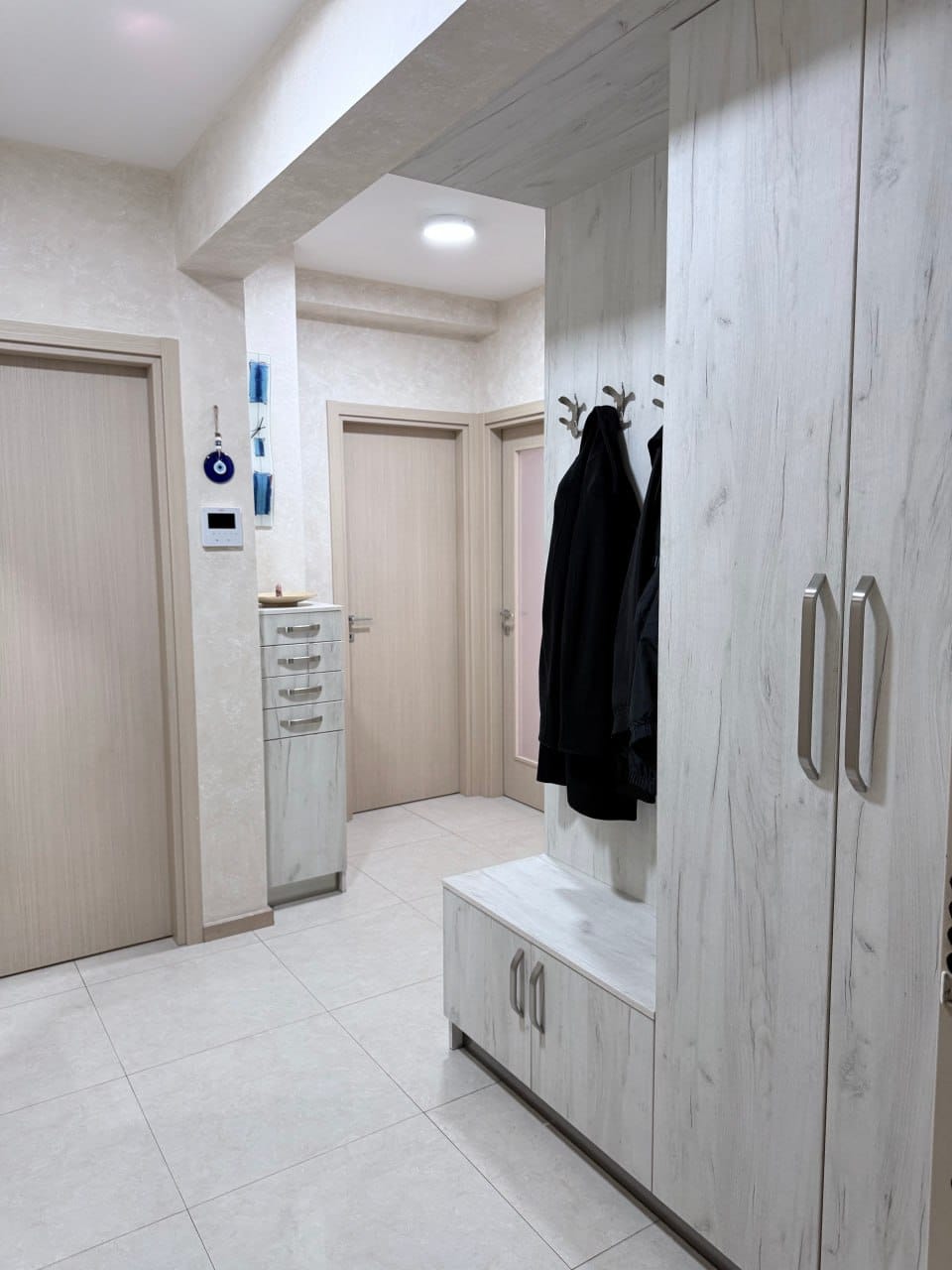 Bright hallway with a built-in wardrobe and wood-style furniture in an apartment in Podgorica, Montenegro.