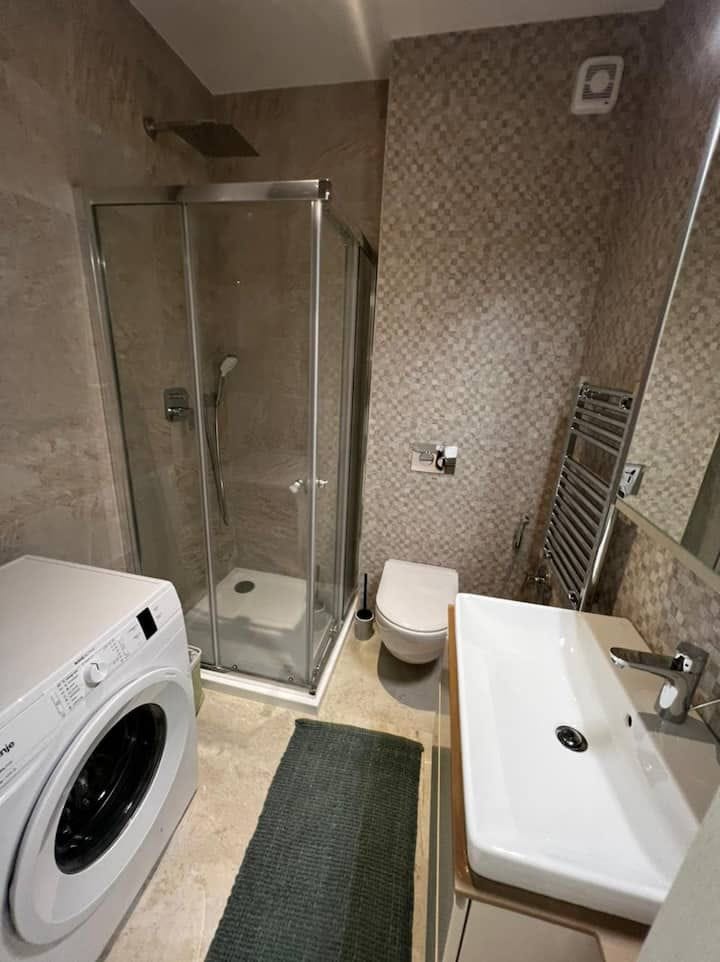 Modern bathroom in an apartment in Kotor, Montenegro: shower cabin, washing machine, and plumbing fixtures.