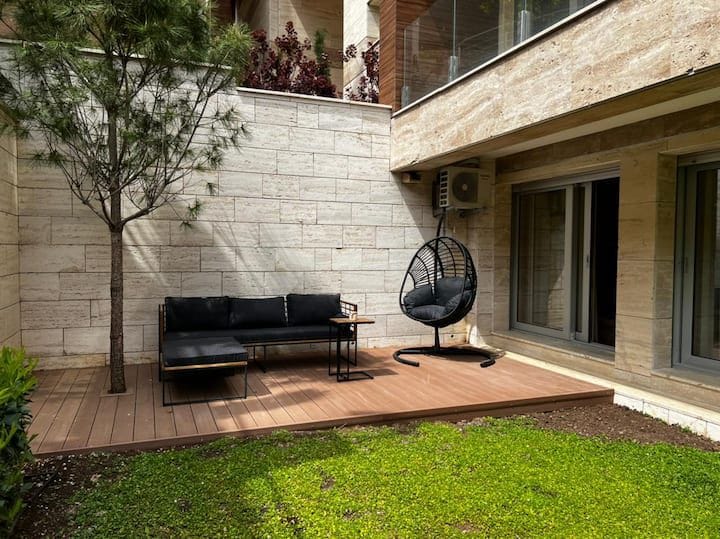 Terrace with wooden decking and garden furniture at an apartment in Kotor, Montenegro. View of a private courtyard with lawn.