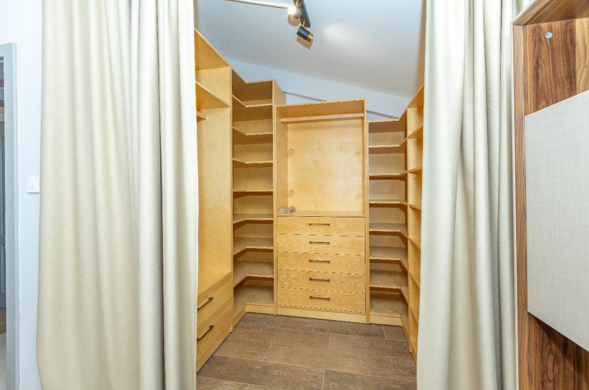 Spacious walk-in closet with wooden shelving and a dresser in a house in Tivat, Montenegro.