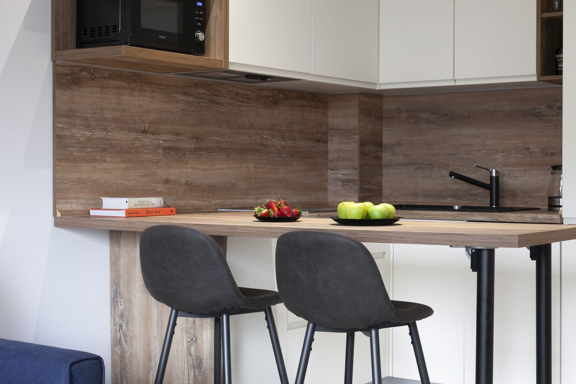 Modern kitchen in an apartment in Kotor, Montenegro: a breakfast bar, dark chairs, and a stylish kitchen set.