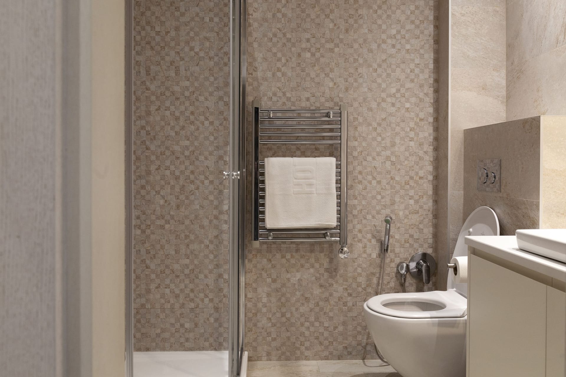 Modern bathroom in an apartment in Kotor, Montenegro: shower cabin, wall-mounted toilet, and towel warmer.